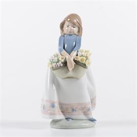 Lladro "May Flowers" Figurine: A Lladro May Flowers figurine. This piece features a young girl in a long flowing skirt holding a basket of flowers. It is marked, “Lladro Handmade in Spain Daisa 1987” and “5467” to underside"