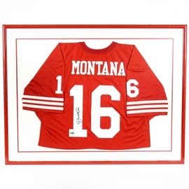 Joe Montana 49ers Autographed and Framed Sports Jersey: A ‘49ers red and white football jersey, autographed by retired football quarterback great, Joe Montana. The jersey is marked “Montana” in white lettering to the upper back, with the number 16 in the center, and a “1” and “6” on either sleeve. Montana’s signature appears in black ink on the number “1” of the number 16 on the center back of the jersey. The jersey is presented within custom red and white double mats, under glass, in a red metal frame, and is ready to hang.