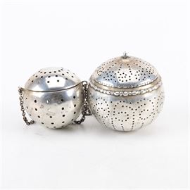 R. Blackington Co. and Gorham Sterling Silver Tea Infusers: A pairing of sterling silver tea infusers. Each one has a spherical shape that features perforated sides and top, attached to chain. This includes a smaller infuser by R. Blackington Co. of North Attleboro, MA (active 1862-1967), marked “Sterling R B Co. 7150” to the underside. It is presented with a bead-and-reel accented infuser by Gorham, stamped with the three pseudo hallmarks of a lion, an anchor, and a Gothic ’G" alongside “Sterling B3621”. The total approximate weight with chains is 1.645 ozt.