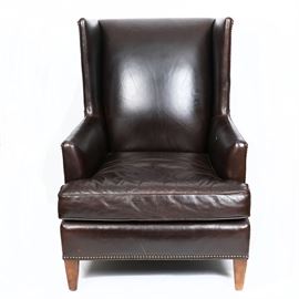 Full Grain Leather Club Chair By Mitchell Gold + Bob Williams: A full grain leather club chair by Mitchell Gold + Bob Williams. This full grain leather chocolate wingback club chair has a removable fitted cushion and a decorative line of bronze tone finish convex tacks on the skirt over café au lait stained square tapered wooden legs. Marked under the cushion: Mitchell Gold + Bob Williams.