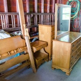 Maple Chippendale Style Four Piece Bedroom Set by Kling: A four piece maple bedroom set in Chippendale style by Kling Furniture, including a bed frame, a chest of drawers, a dresser with mirror, and a nightstand. They are marked inside the drawers and on the backs/ bottoms of the frames.
The chest of drawers, dresser, and nightstand have beveled top and bottom edges, scalloped aprons, and ogee bracket feet, with dovetail jointed drawers which have bails on batwing plates. The chest of drawers has four small drawers over three large drawers. The nightstand has a small drawer over open space with cord hole, over another drawer. The dresser has a wooden framed, removable mirror and four shallow drawers over four larger drawers, in two stacks. 
The bed frame’s headboard and footboard scroll back at the top of the solid panels, set between vase and ring turned posts; the footboard has a turned bar set over the panel. The side rails are plain and support slats are included.