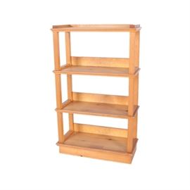 Pine Bookcase: A pine bookcase. The bookcase has four fixed shelves with routered edges. They are supported by a series of vertical square posts. There rails at the back of the three lower shelves and a small gallery around the topmost one.