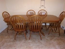 Furnish your dining room with a durable and long lasting rectangular dining table. The table has an elegant trestle base and beautiful scalloped edges for a traditional American style. It's made completely out of solid oak, making the base extremely strong and durable. Features of this table include rounded edges, brass leaf alignment pins, heavy duty brass sash locks, and the dual ball bearing cable glide extension mechanism for a smooth operation. Also included are two 18 inch  leaves that expand to accommodate eight guests comfortably. 4 side chairs and 2 arm/captain chairs.