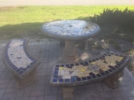 Concrete outdoor table and five benches with mosaic top.