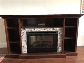 Stacked stone electric fireplace with wood mantel and bookcase surround.