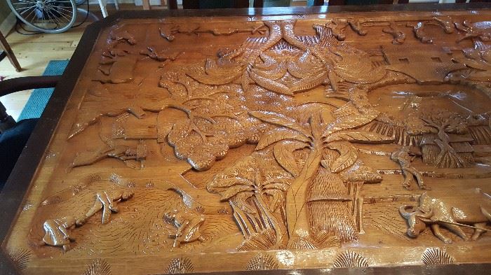 One-of-a-kind hand carved table with glass top featuring farm animals/trees & misc. Solid, one piece of mahogany.