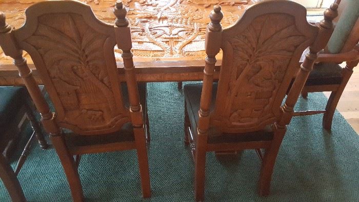 Hand carved dining room chairs with matching scenes from the table top.