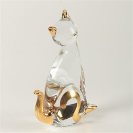 Art Glass Cat Figurine: An art glass cat figurine. The cat is formed of glass with a painted gold toned tail, feet, ears and whiskers. The cat has no facial features but a nose. The piece is unmarked.