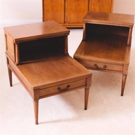 Pair of Vintage Mid-Century End Tables: A pair of matching vintage mid-century end tables. Each end table, made of walnut, has a top hutch for additional storage or display space and a single drawer with rosette mounts and angular bail handles. Each tapered leg has a band of brass at the top. Unmarked.