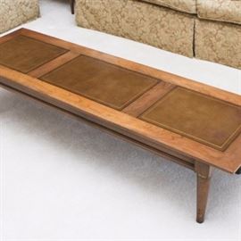 Mid Century Modern Walnut Coffee Table: A Mid Century Modern walnut coffee table with four tapered legs. The top features three rectangles of inlaid leather bordered by imprinted black and gold designs.