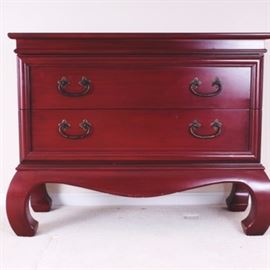 Red-stained Wooden Chest of Drawers: A wooden chest of drawers with a red stain finish. The chest stands on four bowed legs and features two generously sized drawers, each with two metal pulls with bail handles mounted on rosettes. Manufactured by Gallery Designs.