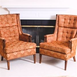 Pair of Upholstered Armchairs: A pair of identical upholstered armchairs. Each chair consists of a wooden frame and is upholstered with a red-orange, brown and tan patterned fabric with tufted backs and exposed wooden feet and knuckles.