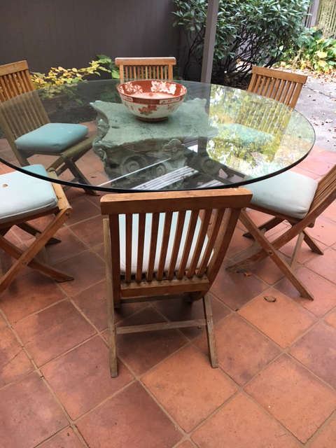 Glass top pedestal table shown with teak chairs 