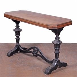 Victorian Style Console Table: A Victorian style console table. This table features a rectangular top with geometric inlay pattern to the apron that rises above turned legs. The legs are connected by a stretcher with arch and floral motif to the center and terminate on a trestle base.