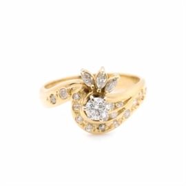 18K Yellow Gold Diamond Ring: An 18K yellow gold 0.63 ctw diamond ring. This ring features a center diamond set above offset shoulders adorned in round brilliant cut and marquise cut diamonds.