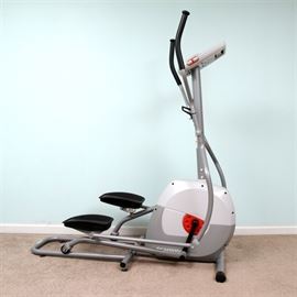 Schwinn A40 Elliptical Machine: A Schwinn A40 elliptical machine. The machine features two-toned gray metal and plastic framing, a battery-operated digital interface with seven preset resistance-based workouts, and a built-in water bottle holder. It is presented with its original owner’s manual.