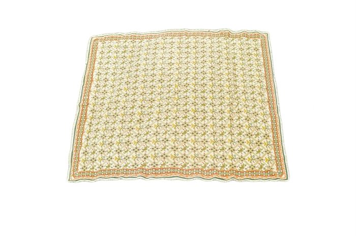 Handwoven Portuguese Arraiolos Area Rug: A handwoven Portuguese Arraiolos area rug. This wool rug is hand-stitched in a palette of cream, saffron, celadon, teal, tomato, cerulean, and shades of green. It features a diamond- lattice pattern grounded in cream, each panel enclosing a tulip with a saffron bloom. Framing the field are compound borders, including a primary border featuring a concentric diamond pattern over cream. The rug finishes on all sides with looped fringe in cream. It is unlabeled.