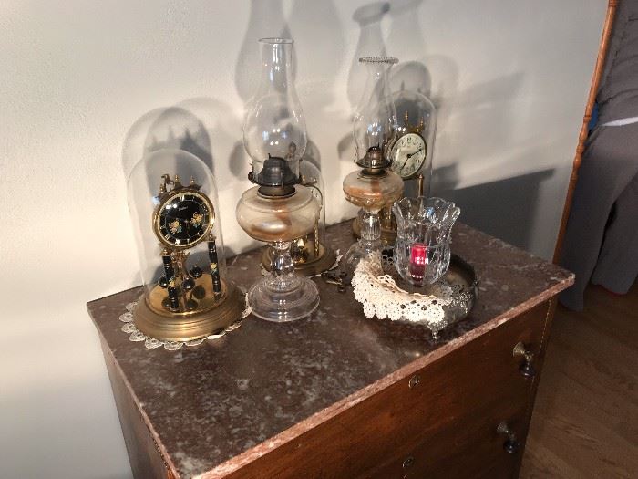 Two anniversary clocks; two kerosene lamps on chest of drawers (chest of drawers not for sale)