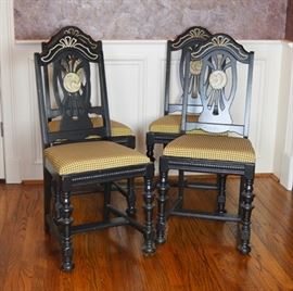 Vintage Black Painted Side Chairs, Set of Four: A set of four matching vintage black painted side chairs. Each chair features an openwork splat with painted center medallion design, with gold tone detailing on the arched top rail. Chairs include a yellow and brown checkered upholstered seat, over a beaded seat apron, turned legs, and flat stretcher. Unmarked.