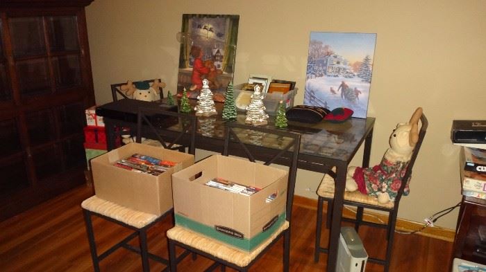 Lovely glass  top metal table with four chairs.    Clean and nice.   Boxes of DVD's too.   Two stuffed bunnies for Easter on chairs and trees on table with two lovely Christmas scene pictures against wall.   X box on floor.  