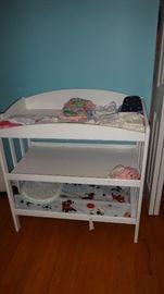 Baby changing table with clothing on top.   