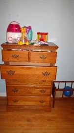 Dresser with children's toys and vaporizer.   Antique/vintage doll bed on floor to right of dresser. 