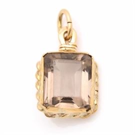 14K Yellow Gold Smoky Quartz Pendant: A 14K yellow gold smoky quartz pendant. This pendant displays a rope motif bordering an emerald cut smoky quartz.