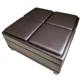 Leather Storage Coffee Table: A leather storage coffee table. This table features a square top with four cushion pads and butlers trays, with pierced handles, to the reverse. The table features thin apron sides and two solid side panels flanking an open storage compartment rising on tapered wooden feet. There are no visible maker’s marks.