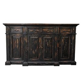 Contemporary Distressed Console: A contemporary distressed console. This piece features a framed plank top over a set back case with three aligned, dovetailed drawers and four hinged cabinet doors. The drawers and cabinets are fitted with darkened brass plated hardware. The piece is painted a flat black and purposefully sanded to expose the raw wood.