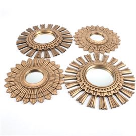 Sunburst Wood Framed Accent Mirrors: A group of sunburst wood framed accent mirrors. There are four mirrors included that are each round in shape and feature a variety of sunburst style frames in a gold tone finish. The frames are decoratively carved and feature hanging holes along the back.