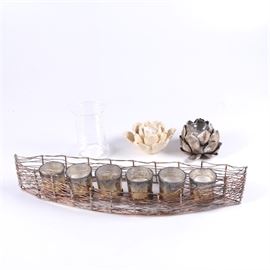 Assortment of Decorative Candle Holders: An assortment of decorative candle holders. This assortment includes a pair of flower shaped candle holders, a metal oval shaped like a boat to hold six candles and a glass cylinder candle holder.