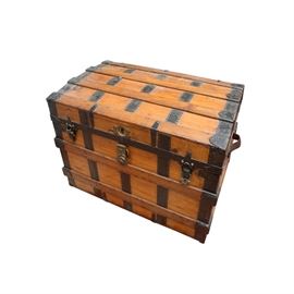 Antique Wooden Steamer Trunk: An antique wooden steamer trunk. This pine bodied trunk is reinforced with bands of oak and metal straps, including corner protectors. It features leather handles and metal latches. The interior includes a removable accessory tray with webbing on the base and a cloth lining. Unmarked.