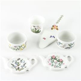 Portmeirion "Botanic Garden" Tableware: A selection of Portmeirion Botanic Garden tableware and decor. This set includes two ramkins, one pie server, one votive candleholder, and two tea bag receptacles featuring the Botanic Garden pattern that depicts a variety of different flowers. Each piece is marked “Portmeirion Botanic Garden Made In Britain” to the base.