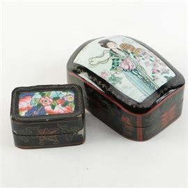 Pair of Asian Influenced Lacquered Trinket Boxes: A pair of Asian influenced lacquered trinket box. This pair offers black lacquered boxes with one showing a female figural image to the lid along with floral motifs. The other box features vibrant floral motifs to the lid, with rope, and floral motifs. Both boxes go with out any visible markings.