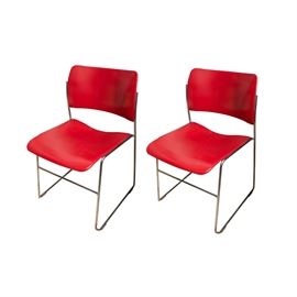 Pair of Modern Red Stacking Chairs: A pair of Modern red stacking chairs. The two chairs feature shaped red plastic backs and seats attached to bent metal frames.