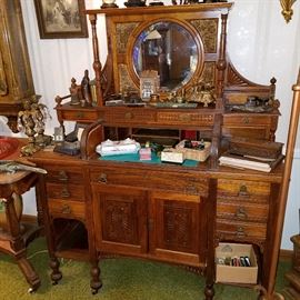 Walnut ornate desk/cabinet with roll top over writing surface. 4 panels surrounding mirror are punched brass, popular in the 1880's.  Displays collection of ink stands & dip pens