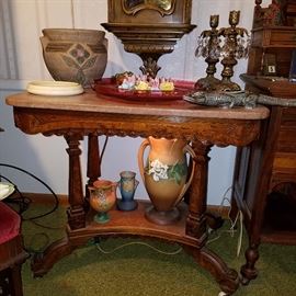 Victorian solid walnut marble top table with added light shining above lower shelf.  Displays Roseville & other pottery.