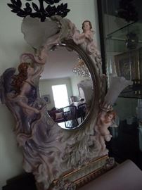 Art display with mirror. It is a table mirror with a figurine theme in porcelain . Also has two lights.