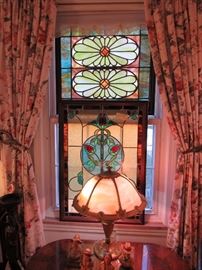 Below these gorgeous stained glass windows you will find a Victorian parlor table, western-themed Anri carvings and an Amber Slag Glass lamp with brass base. 