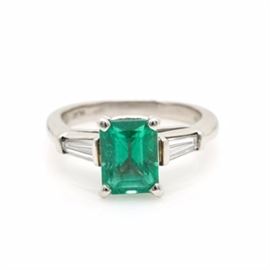 Platinum Emerald and Diamond Ring: A platinum synthetic emerald and 0.50 ctw diamond ring. This ring features an emerald center stone prong set between diamond side stones.