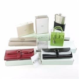 Wolf Designs Jewelry Boxes, Jewelry Rolls, and Travel Cases: A collection of Wolf Designs products. The selection includes four rectangular jewelry roll cases in red, light tan and black leather; an off-white leather jewelry box featuring a mirror lid interior and a compartmentalized interior; a rectangular jewelry box in beige also featuring a mirrored lid and compartmentalized interior; a travel jewelry box in a chartreuse green alligator embossed leather with dual handles, hinge opening and flap closure with a compartmentalized storage interior; a brushed silver-tone flask in a formed black leather base. Most pieces include original packaging and are new.