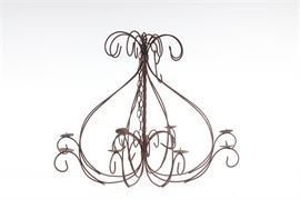 Wrought Iron Candle Chandelier: A wrought iron candle chandelier. The piece has curved metalwork, eight arms with circular bobeches and a spike to accommodate a pillar or ball candle. A length of chain link for hanging is included.