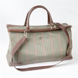 Diane von Furstenberg Travel Tote: A Diane von Furstenberg travel tote. The satchel features coated canvas in a green/black/red checkered pattern, brown leather on the trim and dual handles, a top zipper opening, monogrammed silver tone hardware, and protective studs on the structured base. The interior is lined, and includes side wall pockets and a maker’s label. This selection includes a detachable webbed shoulder strap.