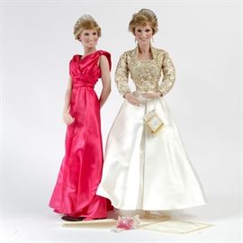 1998 Ashton-Drake "Portraits of Diana Collection" Porcelain Dolls: A pair of vintage Ashton-Drake porcelain portrait dolls. This array hails from Ashton-Drake’s 1998 “Portraits of Diana Collection” and includes Diana, Emissary of Compassion and Diana, Visionary of Style. These hand-painted depictions of Diana have short blonde hair topped with tiaras, bright blue eyes, and glossy pink lips. One is clad in a red satin formal gown, the other in a cream dress with a beaded bodice and full skirt. Each is marked on the upper back, and comes with its original packaging.