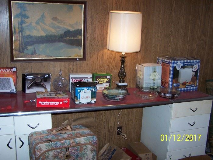 NICE vintage white /red counter top Cabinet, ( in very good condition) Lamp  and ( NIB Bread Maker, small Lamp, 2 Corning Ware, Hair Dryer, Apple Peeler), nice Luggage & more