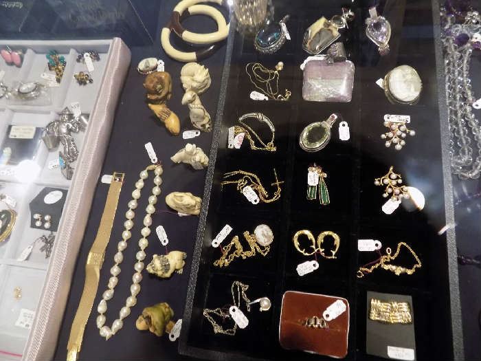 Assorted gold and silver jewelry priced less than $100. Six ivory netsukes at left are reduced 50%.