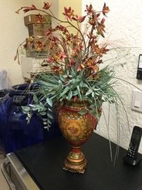 A pair of matching vases in  red and gold, with brass base, each with a silk orchid arrangement 