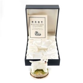 Halcyon Days Trinket Box "West Highland White Terrier": A porcelain and enamel trinket box from Halcyon Days. This item is the West Highland White Terrier and is in the form of the breed. The upper piece of the box is made from porcelain and the base is made from enamel. There is a bronze tone metal frame with a hinge that opens the box. The interior of the box is marked “HD London JS” and has a a simple drawing of a West Highland Terrier. The underside of the box has information about the history of the breed. This item is presented with a pamphlet in it’s original satin lined box.