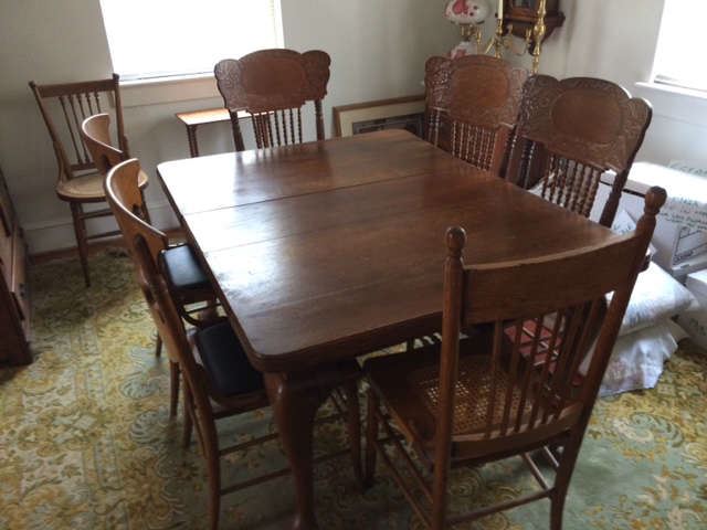 Antique oak dining table with 6 pressed back chairs. Some with cane bottoms, some covered.  