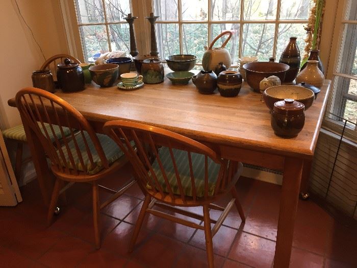 Table and three chairs with large selection of pottery.